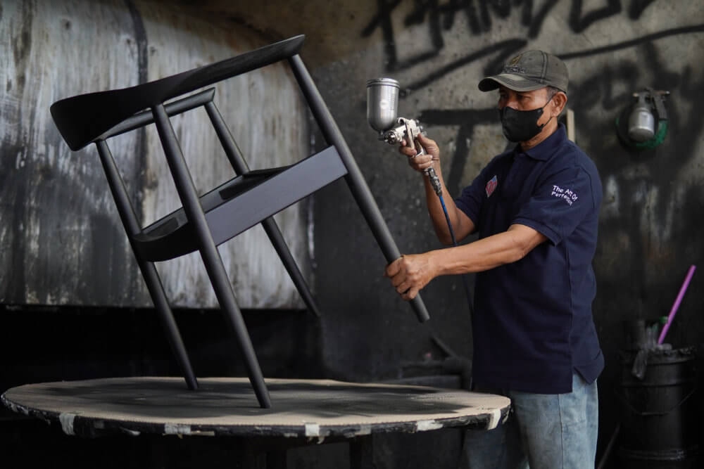a worker painting or finisihing furniture frame at Indonesian Furniture Manufacturer (MPP Furniture)
