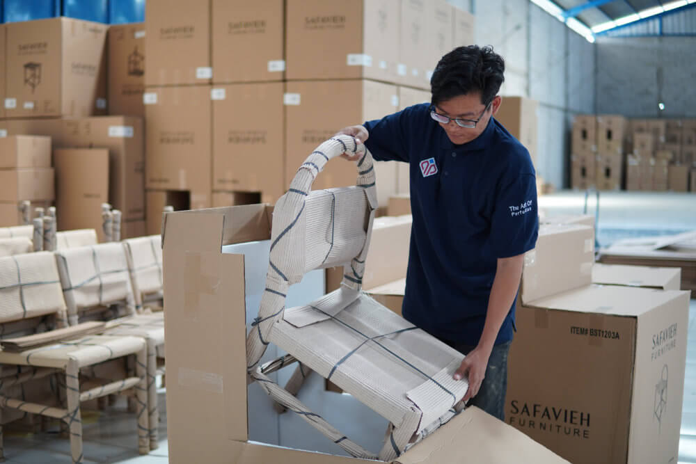 A worker put finished furniture ready for export in carton box