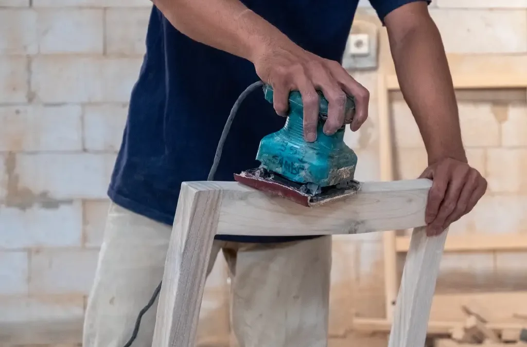 Artisan from indonesian furniture manufacturer sanding custom teak chair