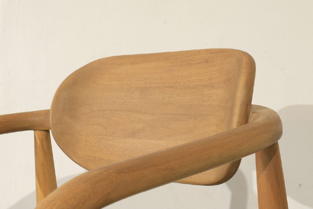 Close-up view of a wooden dining chair with curved backrest and smooth natural finish