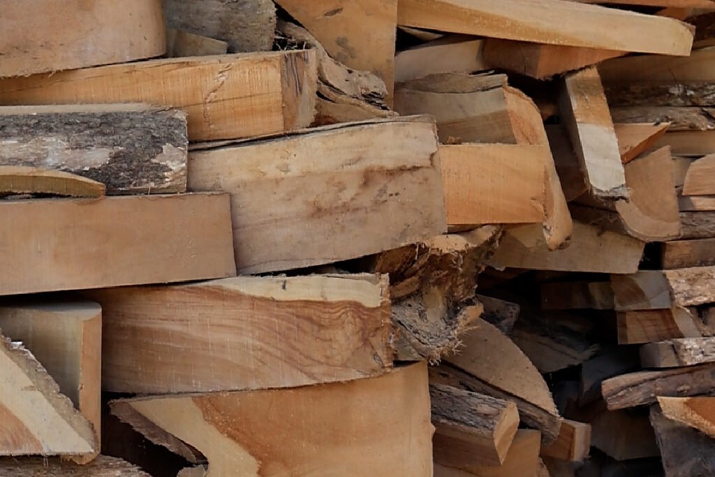 Stack of raw teak wood planks prepared for curved furniture production.