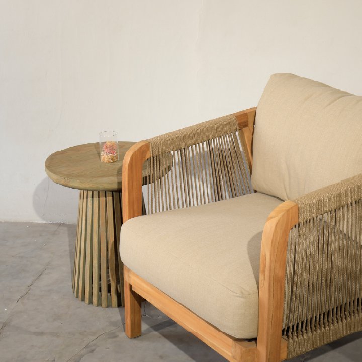 Teak rope lounge chair with cushion paired with round teak side table outdoor, ideal for patios and resort lounges.