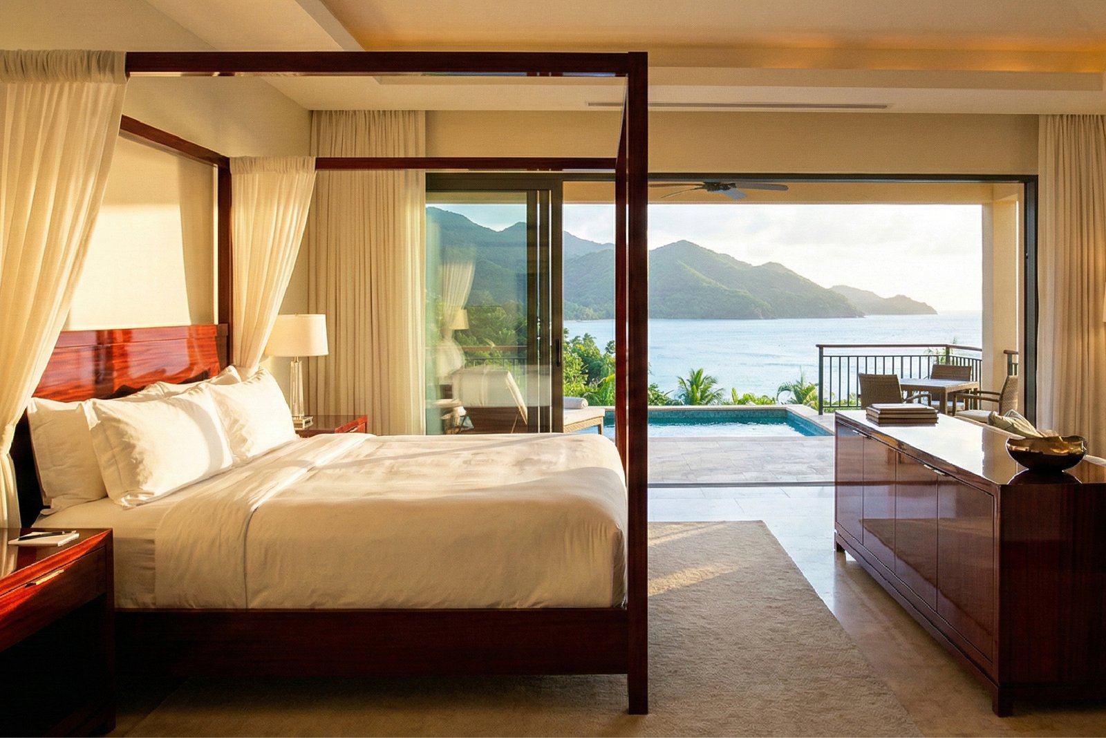 Highly finished mahogany four-poster bed and sideboard, defining the ultimate Luxury Resort Furniture for a high-end, tropical ocean-view suite.