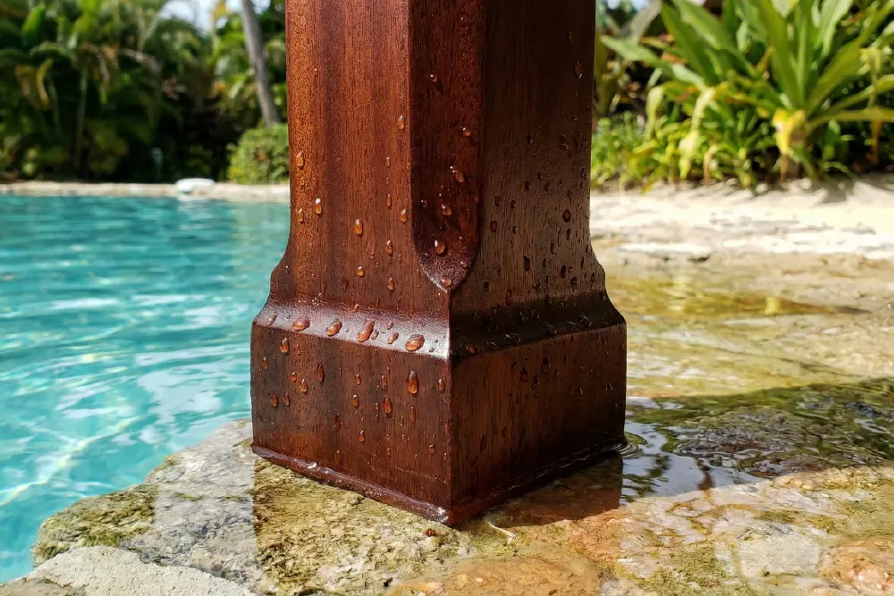 Technical close-up of a mahogany Luxury Resort Furniture leg showing water beading on the rich finish, proving its durability and moisture resistance near a pool.