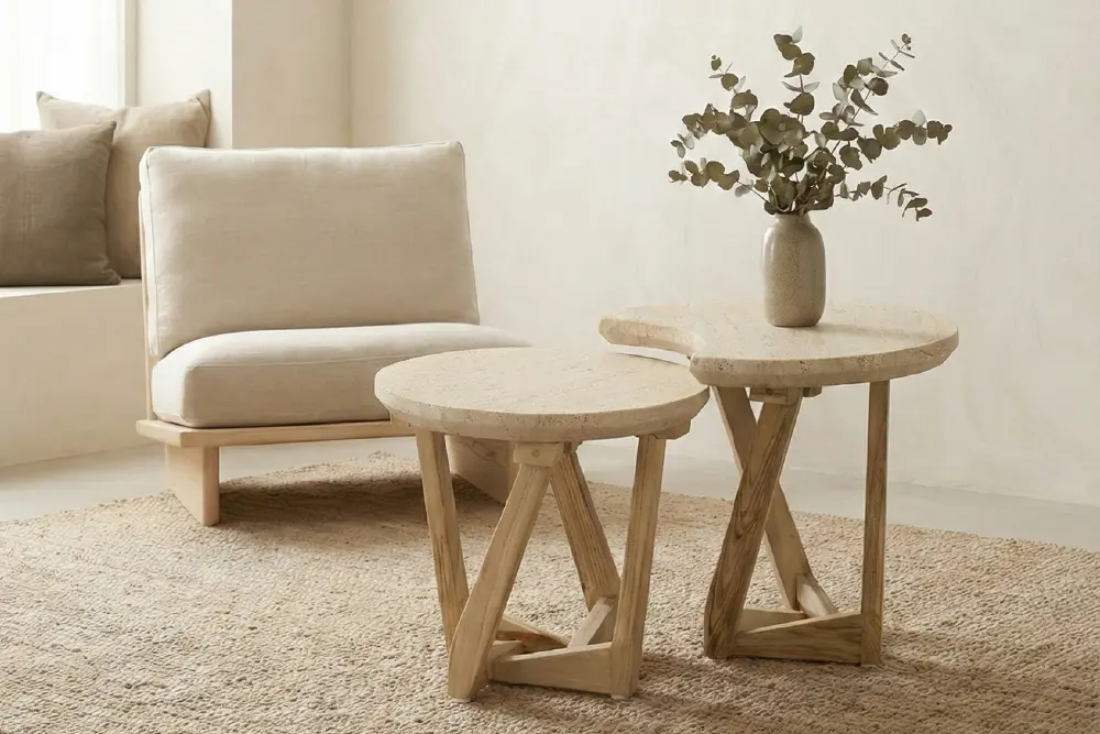 Page Optimize_2-02 Pair of organic-shaped nesting side tables by MPP Furniture featuring textured stone-look tops and wooden cross-base legs, arranged on a woven jute rug next to a beige armless chair.