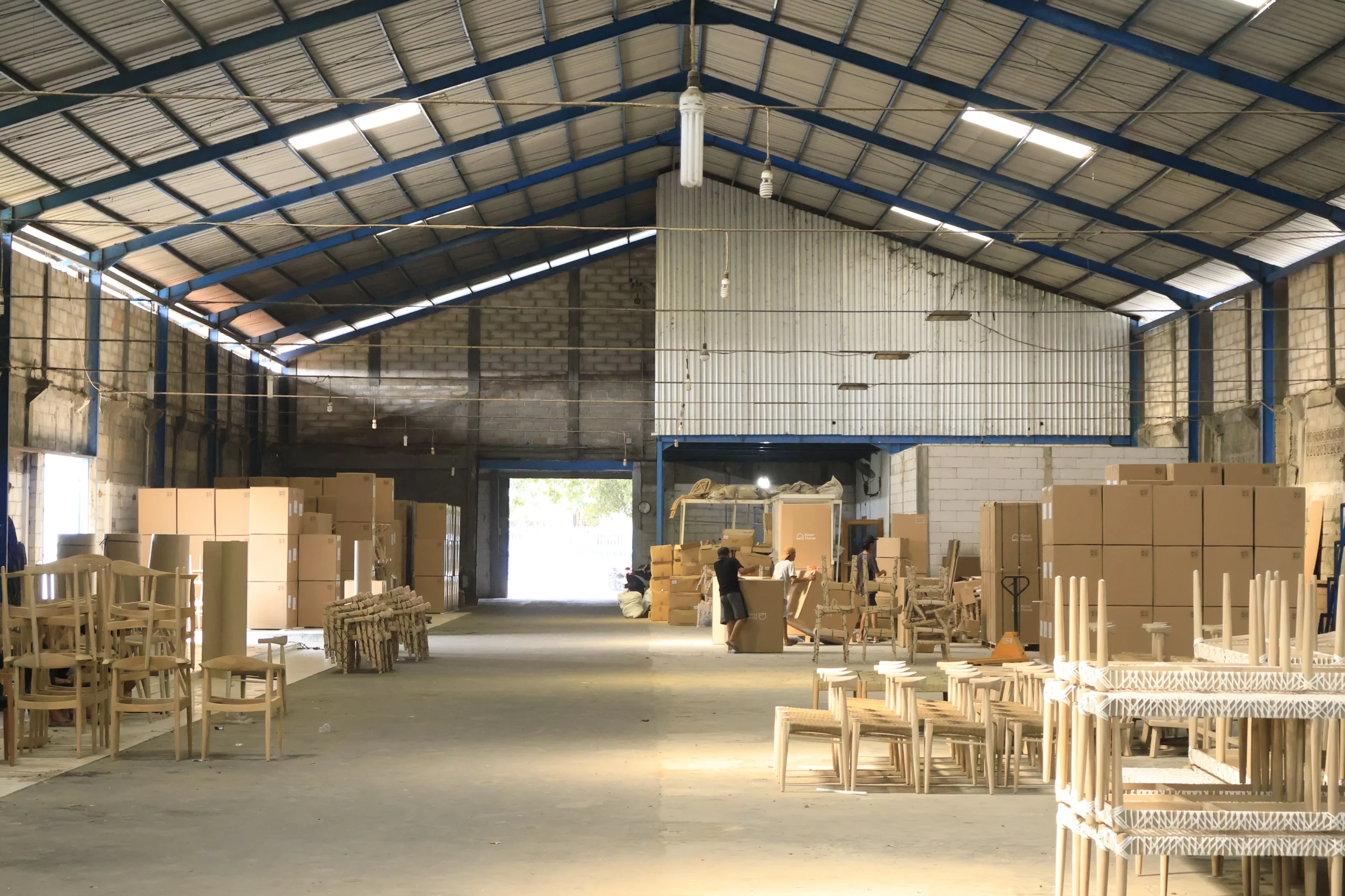 A large warehouse with packed boxes and wooden chairs ready for export, demonstrating reliable Indonesia custom furniture sourcing for commercial projects.