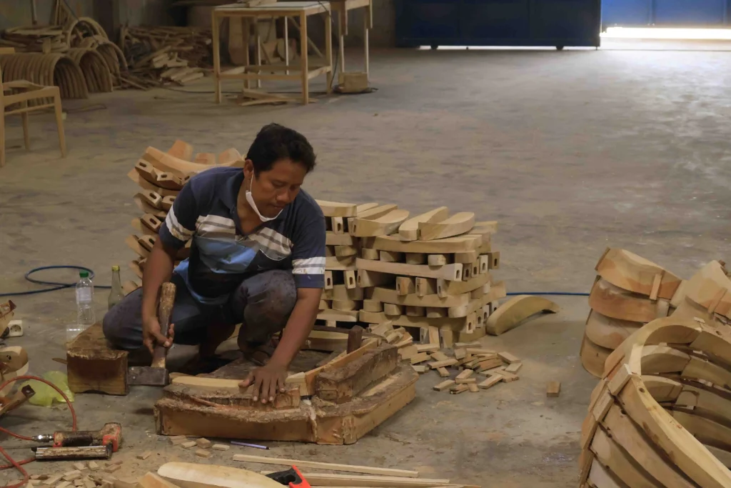 Skilled Indonesian craftsman assembling a frame, highlighting the efficient labor aspect that influences overall mindi wood furniture cost.