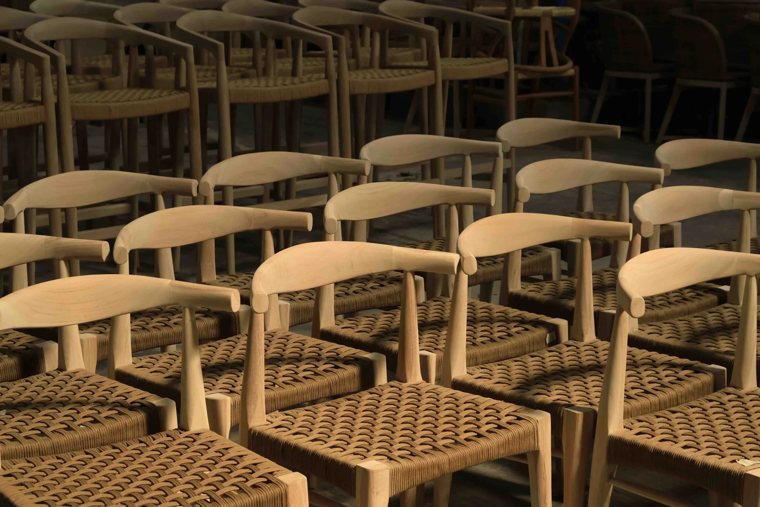 Rows of unfinished dining chairs in an Indonesian factory, illustrating how mass production optimizes mindi wood furniture cost.