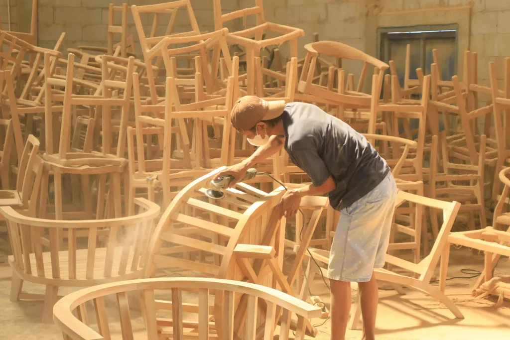 An Indonesian craftsman batching raw wooden chair production to efficiently meet the standard MOQ for furniture retailers.