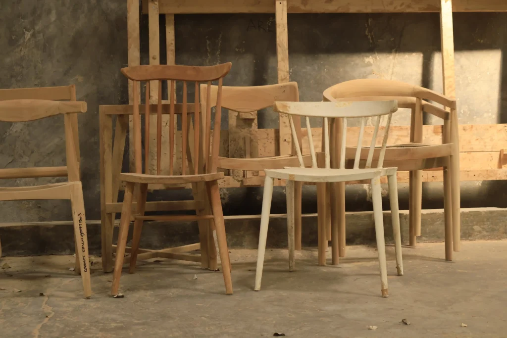 Unfinished raw wooden chair frames in a workshop, representing the quality control and material risks in furniture sourcing.