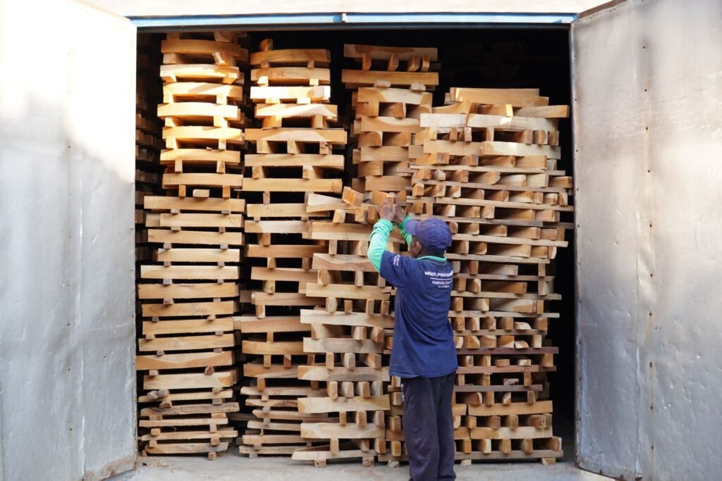 A person placing pieces of wood into a specialized room for drying in indonesian furniture