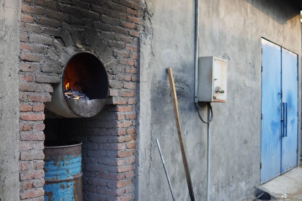 Industrial wood furnace with an active fire beside a kiln drying facility in a indonesian furniture area.