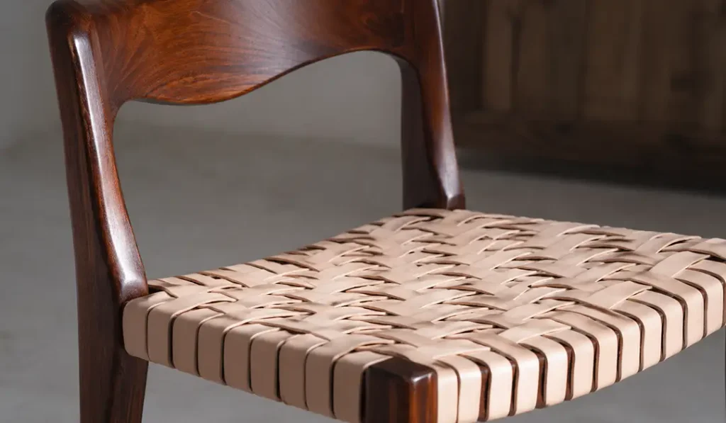 Close-up of teak dining room chair showing visible teak grain and leather seat detail