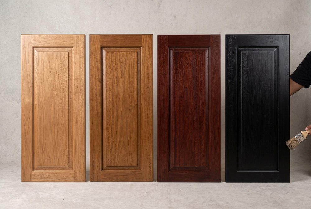 Close-up photograph of four Mindi wood panels side-by-side displaying natural, warm brown, deep red, and sleek black finish optimizations